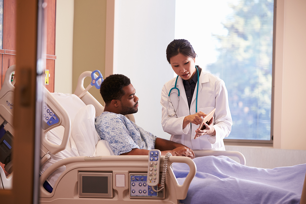 Healthcare Hospital Doctor With Digital Tablet Talks To Male Patient